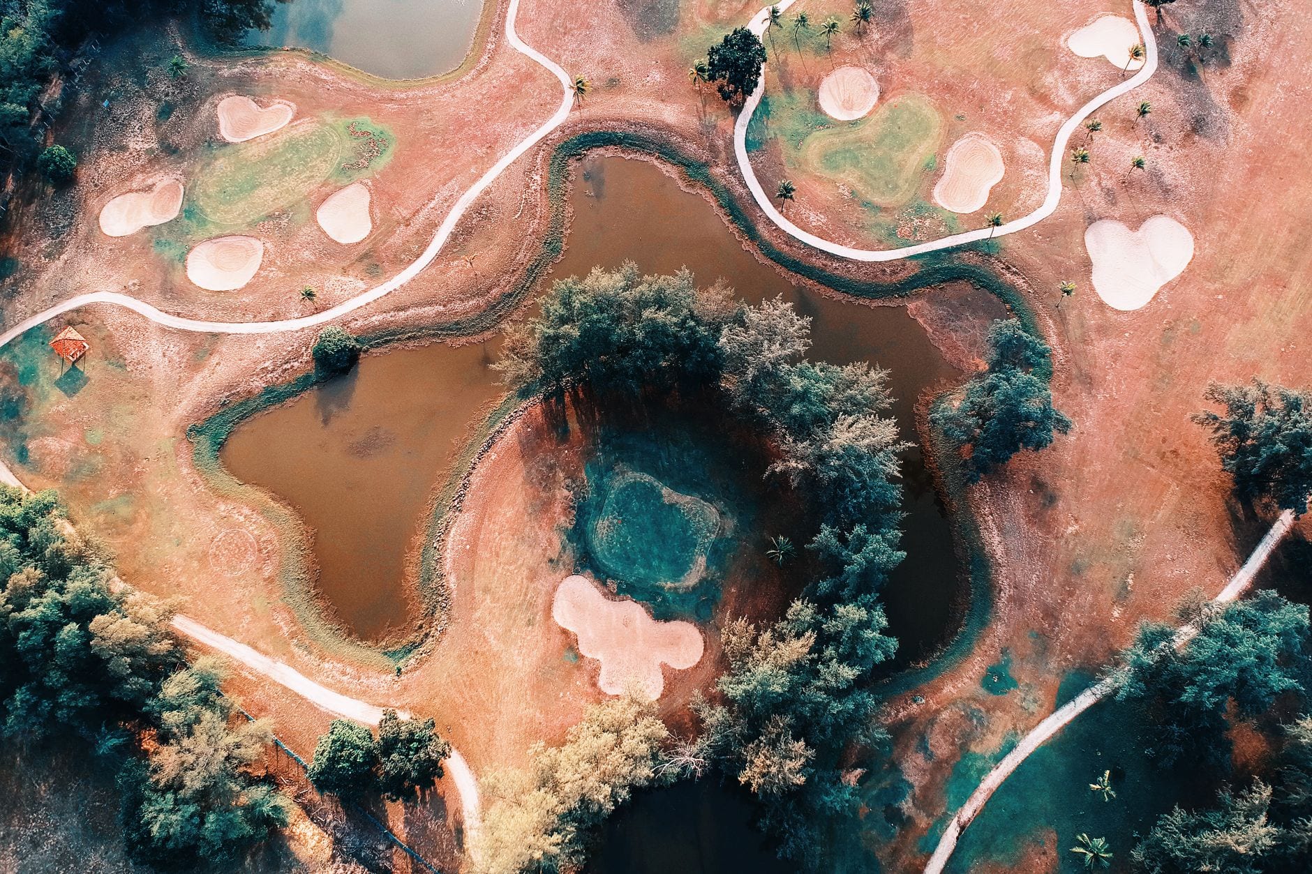 Overhead view of a golf course with pathways and ponds winding through the fairways